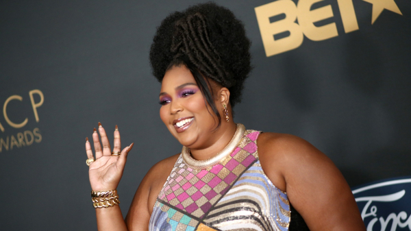 Lizzo smiling on naacp awaards red carpet with purple eye shadow
